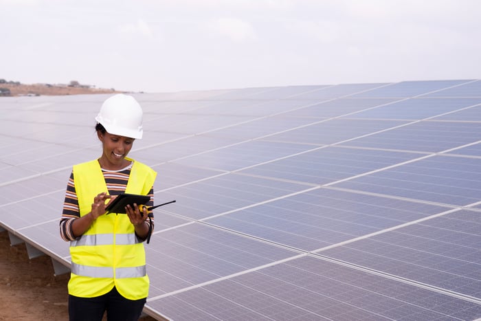 Engineer at a power station with solar panels in the background.