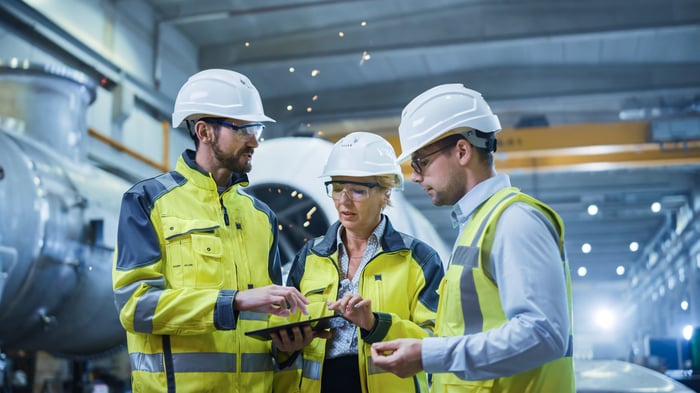 Three heavy industry engineers talking in a pipe manufacturing factory.