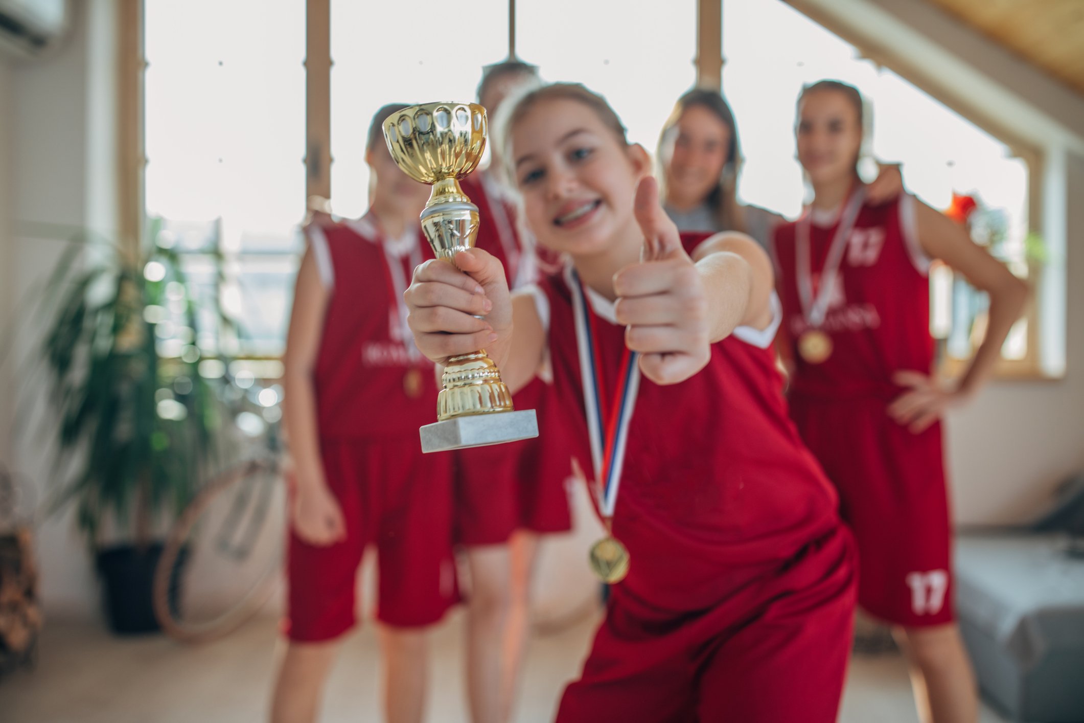 A young basketball player holding a trophy i front of teammates.