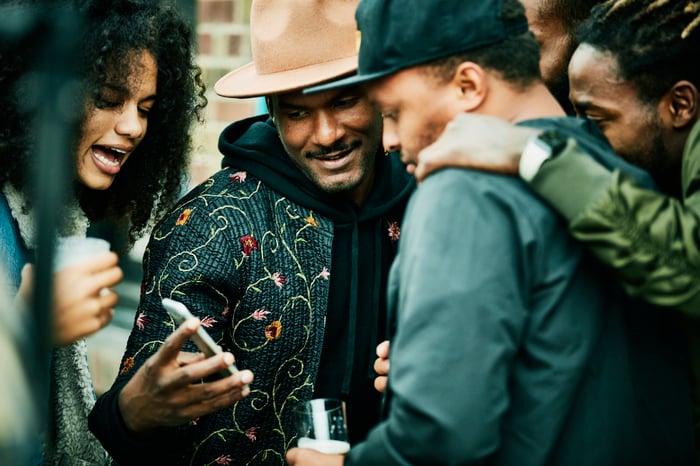 A group looking intently at a smartphone and discussing.