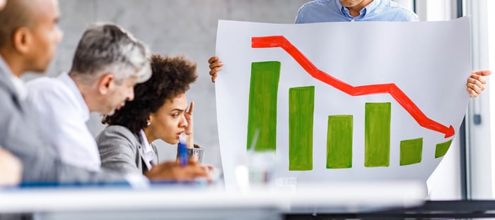 A person holds a piece of paper with a descending bar chart. 