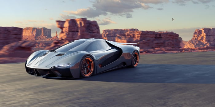 A generic electric sports car driving through a rocky landscape at dusk.