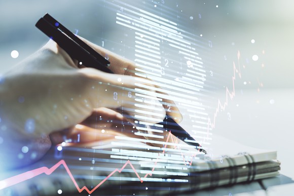 Writing on a notebook with a Bitcoin logo and rising chart in the background.