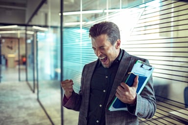 A man holding a book and clipboard cheering.