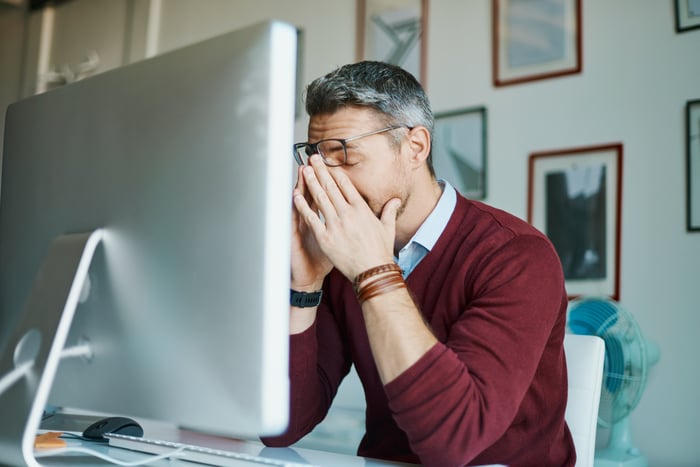 Person at computer with face in hands.