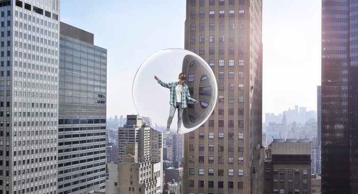 Person wearing a VR headset in a bubble surrounded by skyscrapers.