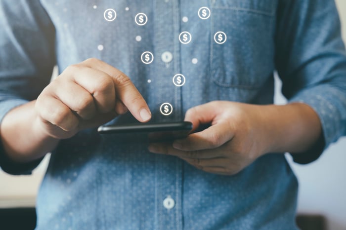 Man with smartphone making cash transactions.
