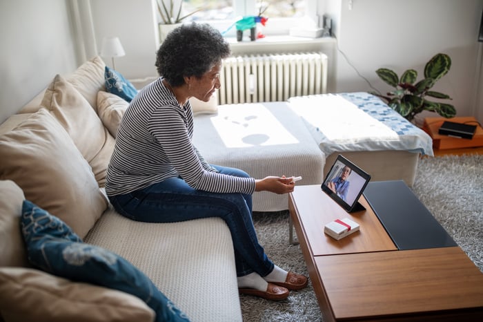 Person in their living room using video conferencing on a tablet.