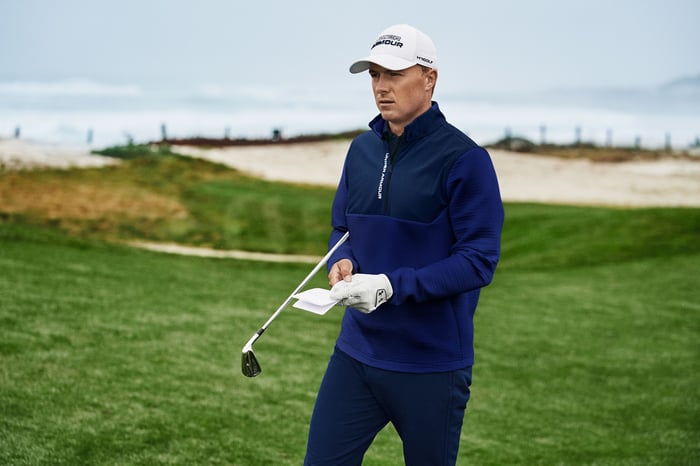 Golfer on the green wearing Under Armour gear and holding a club.