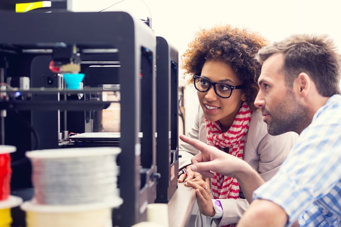 Woman and man use 3D printer additive manufacturing