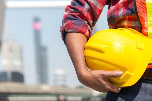 A construction worker holds a yellow hard hat.