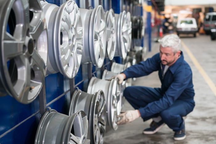 A person working with aluminum alloy car rims at a shop.