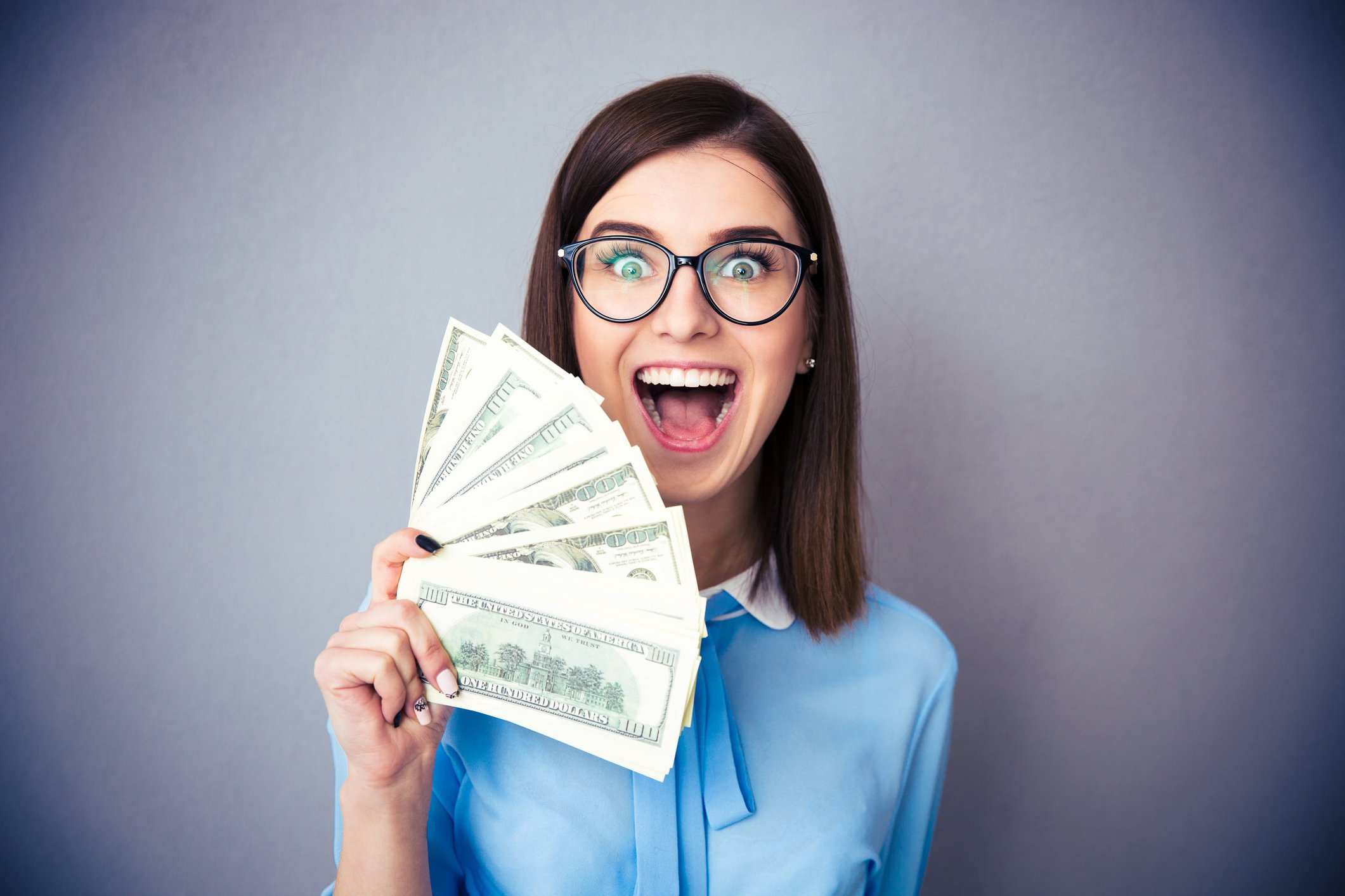 GettyImages-469918218 -- Woman holding money and smiling or shouting