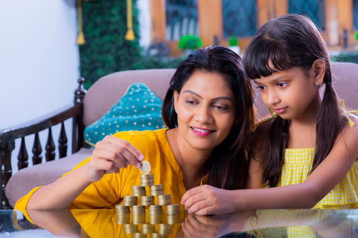 A mother and daughter making piles of coins on a table.