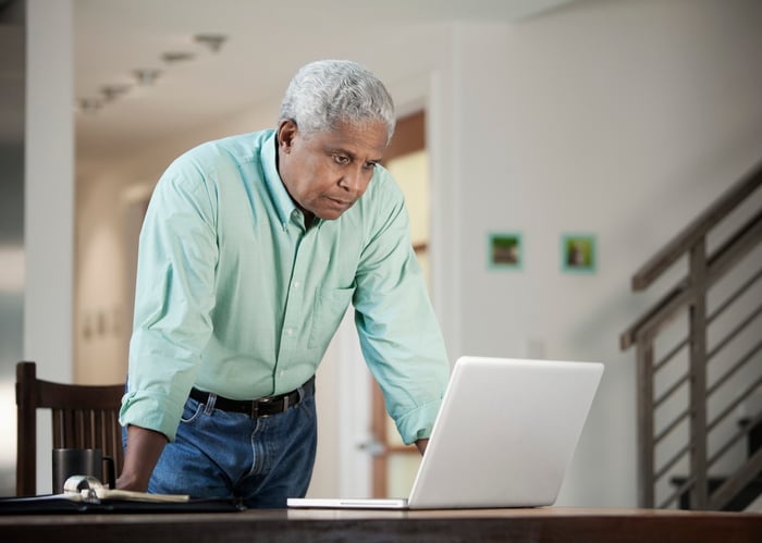 Person with serious expression standing over laptop