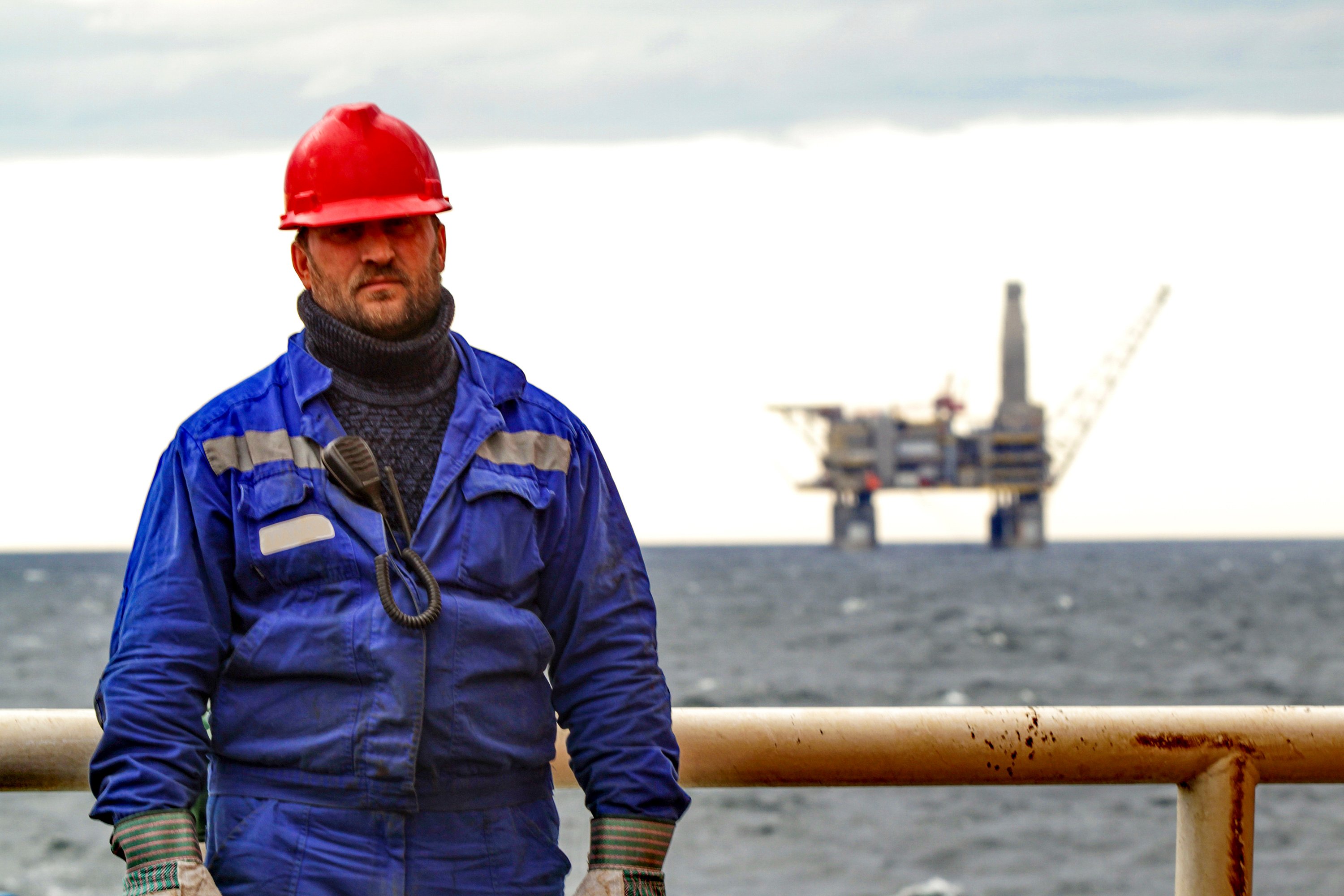 20_11_24 A person in a blue work suit with an oil rig in the background _GettyImages-869933674