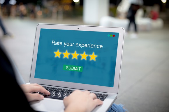 Person's hands on the keyboard of a laptop that says "rate your experience" on the screen.