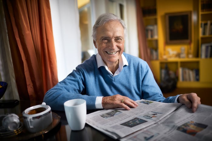 Smiling person at table with newspaper