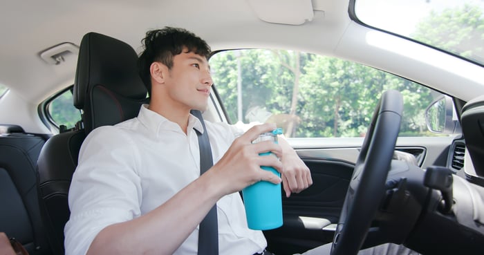 A person relaxing and drinking coffee in a self-driving car.