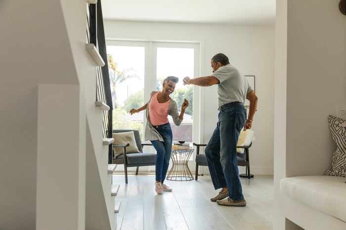 Two people dancing in a living room.