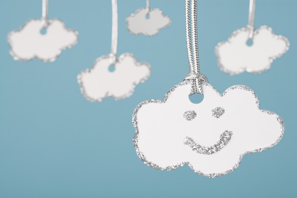 Cloud shaped keychain with smiley face on it.