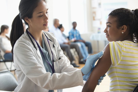 A healthcare worker prepares to vaccinate a teenager.