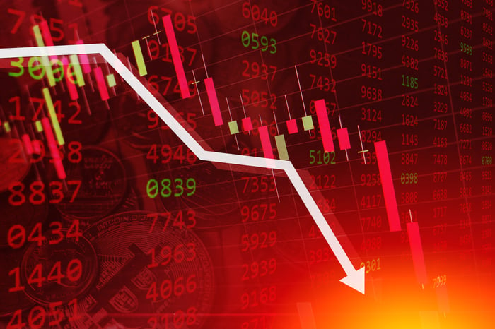 White arrow declining sharply atop a stock tickertape display bathed in red.