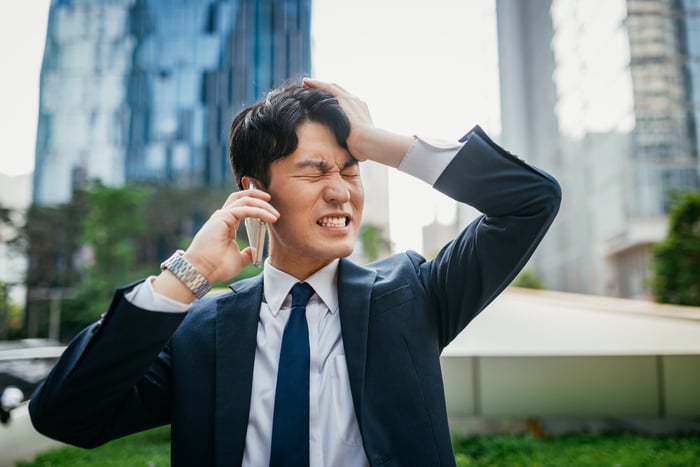 A businessman winces while he's on the phone. 