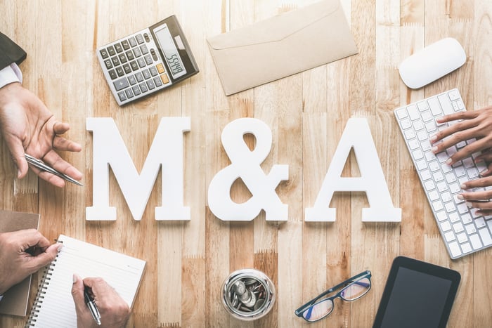 An overhead view of a table with large blocks that say "M&A" and hands working.