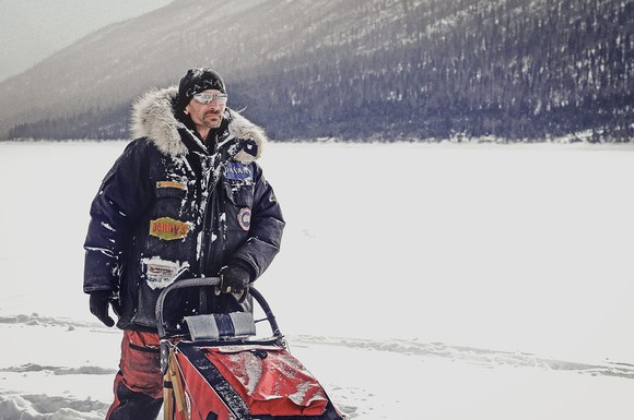 Person with sled wearing parka in snowy valley.