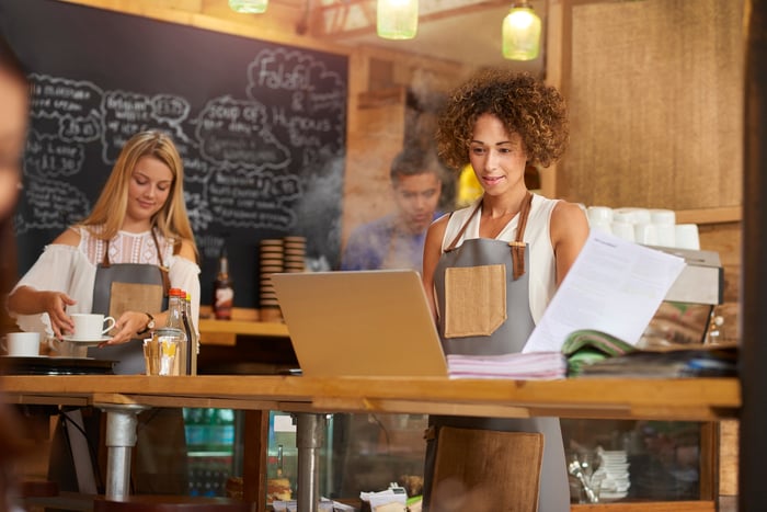 Small business owner in cafe doing accounting paperwork