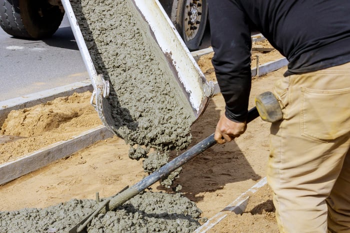 A construction worker dispersing cement from a cement truck.