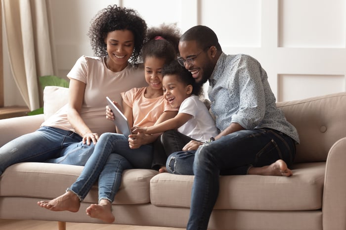 A happy family sitting on the couch viewing a tablet device.