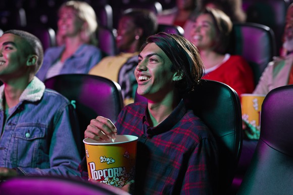 A person eating popcorn while watching a movie in a crowded theater.