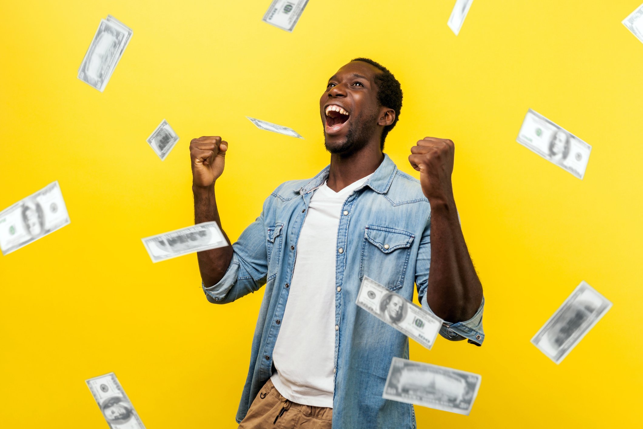 Man shouting and dancing as dollar bills rain down against a yellow background