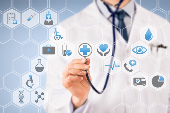 A physician holding a stethoscope up to healthcare icons.