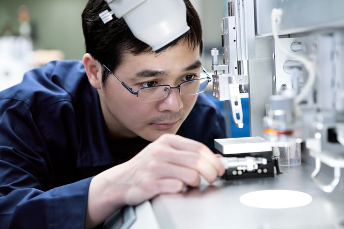 Person closely examining manufacturing equipment.