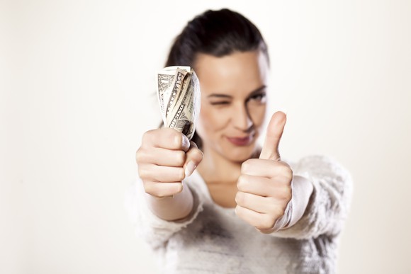 Woman holding money and giving thumbs up.