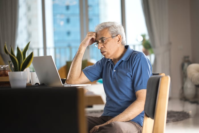 Person at laptop holding head.