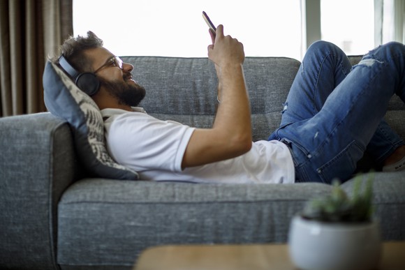 A person wearing headphones and using a smartphone.