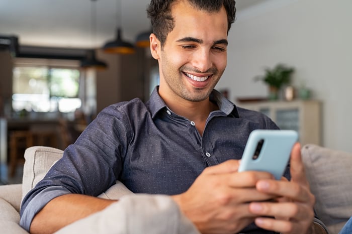 A smiling person looking at a smartphone.