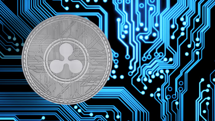A silver-colored XRP token set atop circuitry that represents blockchain.