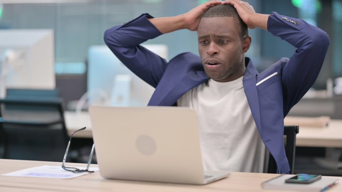 A worried person staring shockingly at his computer screen.