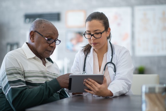 Patient and doctor looking at a tablet.