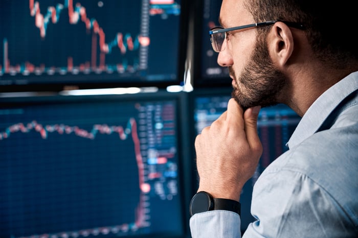 A person analyzing falling stock price charts on computer screens.