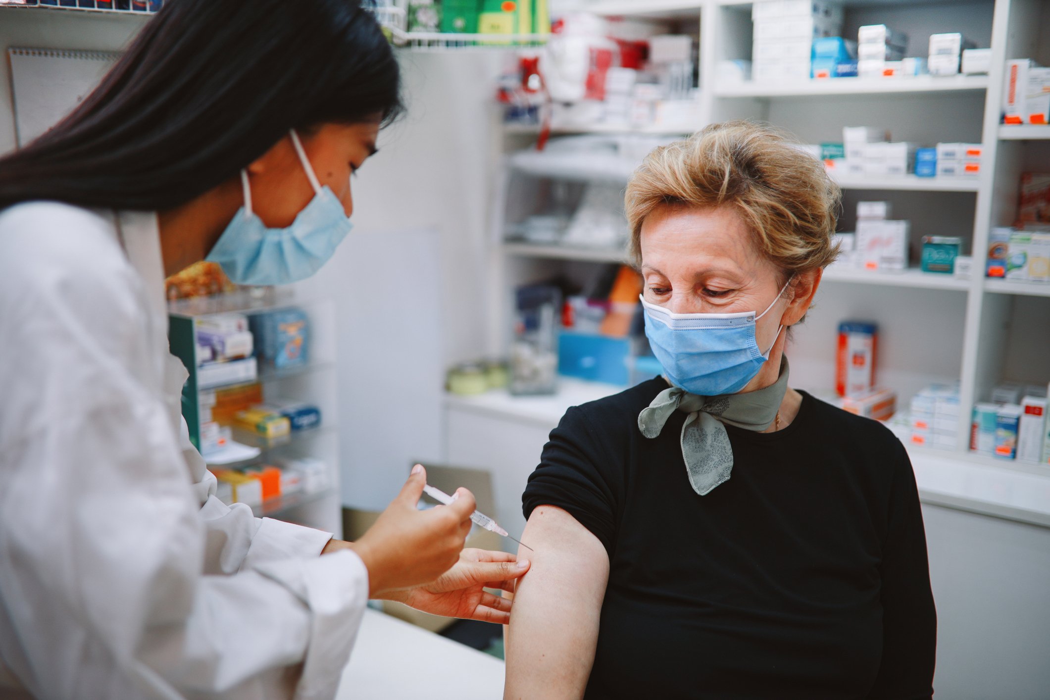 Masked person giving vaccine to another masked person_GettyImages-1280407500