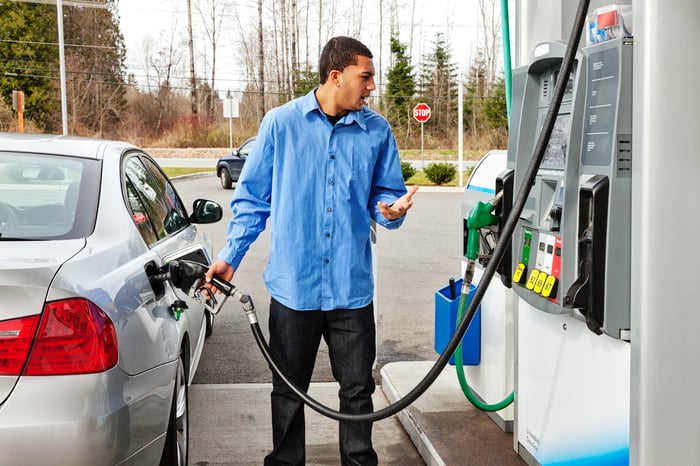 Man is upset at price as he fills up his car at a gasoline pump