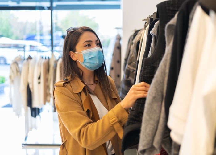 Masked person looking at clothing in store.