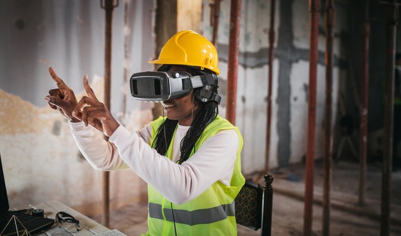 Smiling person using virtual reality simulator on a construction site.
