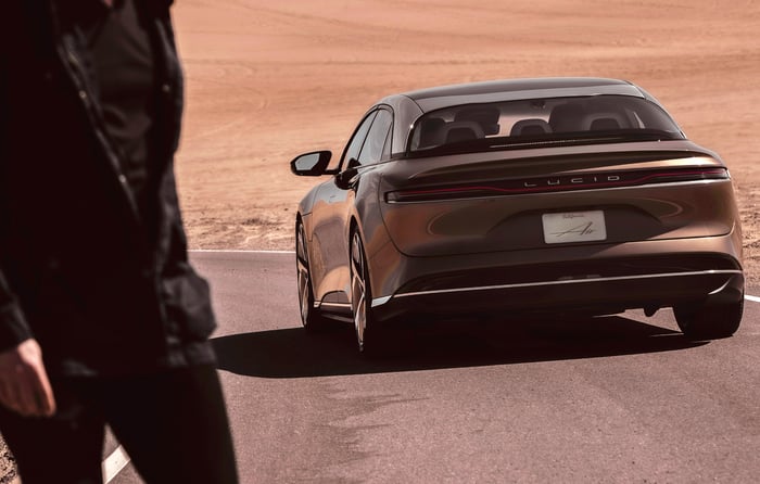 A lucid air driving on a highway through the desert.